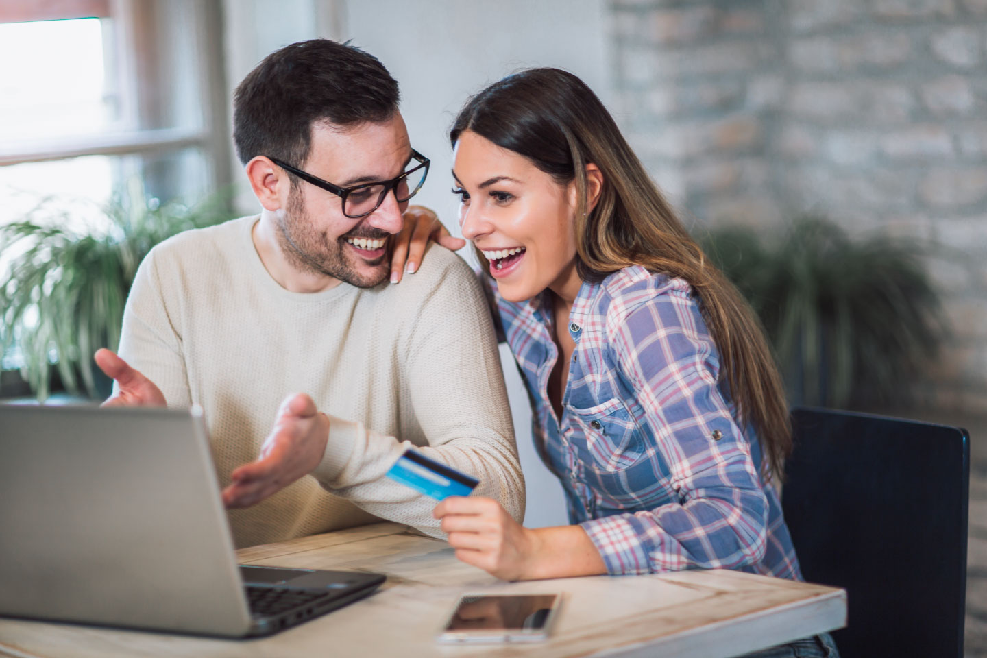 Credit Vision are here to help you get a clear vision of the freedom you deserve Smiling couple using laptop and holding credit card at home